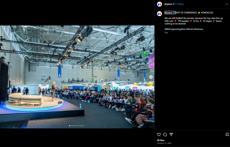 DMEXCO conference stage with large screens and blue/yellow lighting reflecting on crowd