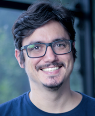 Homem com bigode em camisa azul escura, fundo blurred